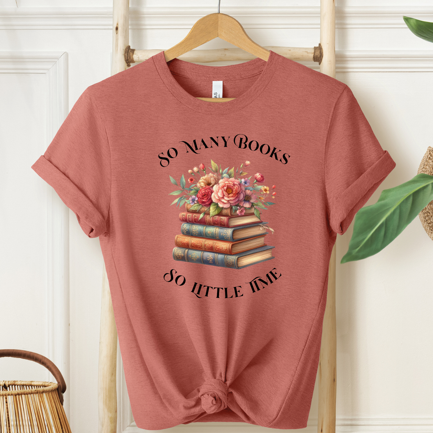 Elegant heather clay t-shirt is perfect book lovers. A bouquet of pink roses perch on a stack of vintage books