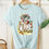 Thumbnail: Blue short sleeve t-shirt with classic vintage illustration of Red Queens guards from Alices Adventures in Wonderland