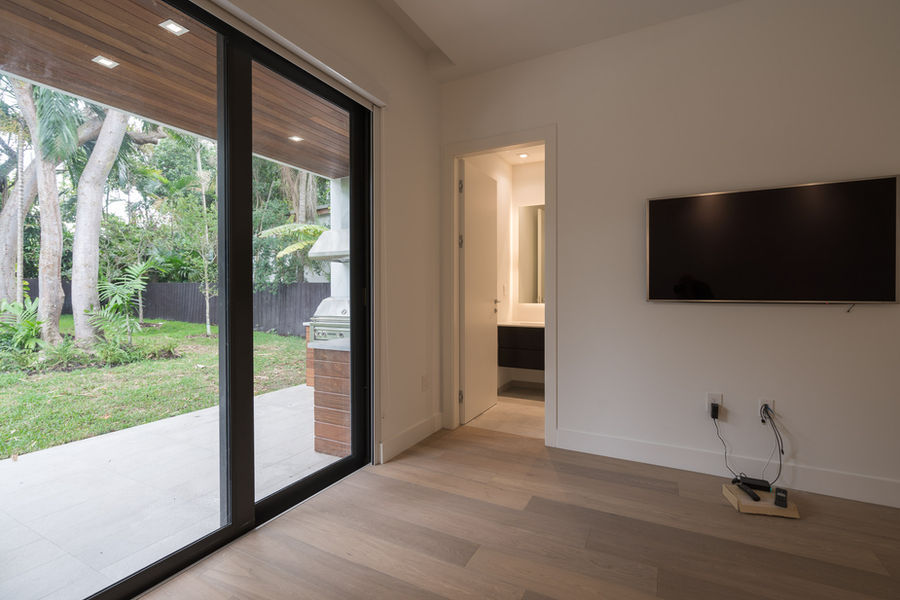 Modern bedroom with sliding glass doors, showing patio and bathroom