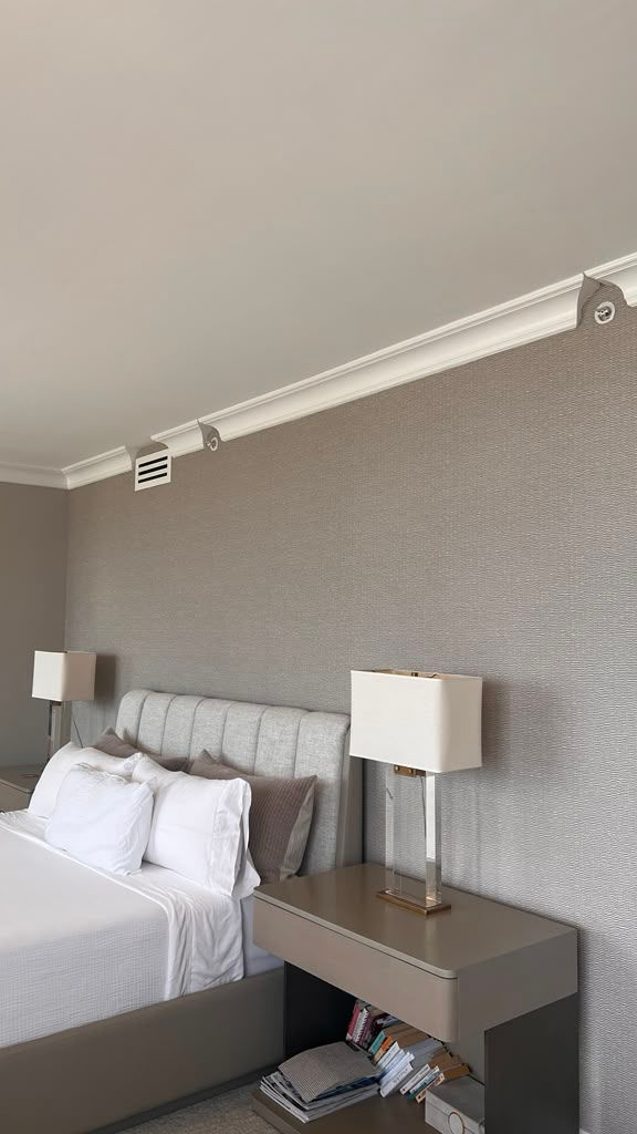 Seamless installation of TWC3383 grey textured wallpaper near me behind a cream tufted headboard and modern grey nightstand in a Miami Beach master bedroom.