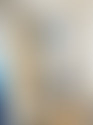 Modern bathroom with white toilet, textured gray wall, glass shower, and lit sconce. Cream sink and beige tiles create a sleek design.