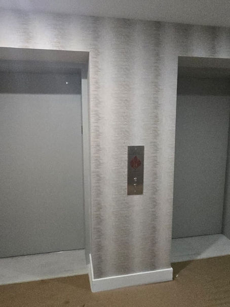     Professional installation of GUH52098 textured wallpaper in Miami inside an Aria Reserve elevator foyer, featuring vertical gray and champagne ombre stripes and a clean white floor transition.