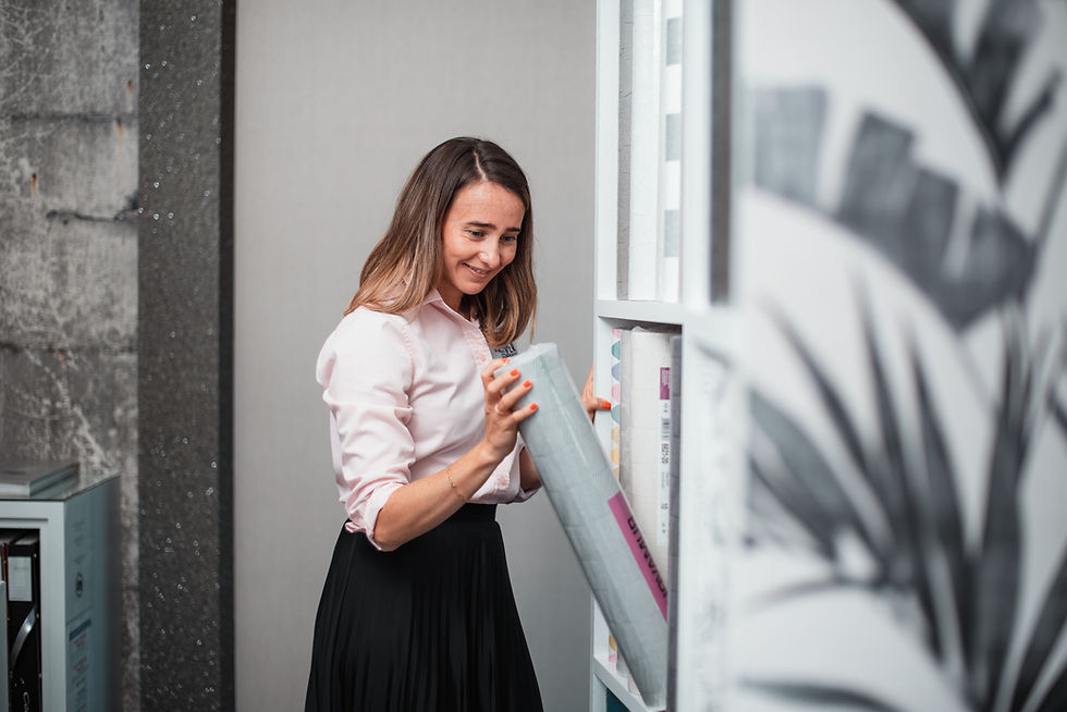 Woman in a pink shirt takes a roll from a shelf. She smiles in a modern setting with gray and white decor. Cozy and focused mood.