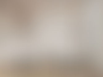 Modern dining room with six black and white chairs around white tables. Large mural of trees on wall, with two pendant lights and large window.