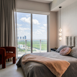 Bedroom with large windows, red chair, and a scenic outside view.