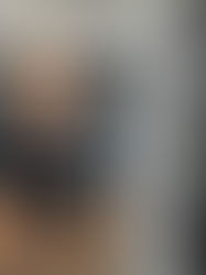 Man smiling in a wallpaper store with patterned rolls and samples. Text: "#DressYourWall." Wearing a gray shirt, cheerful atmosphere.