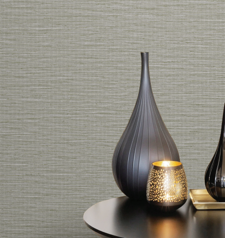 Tall gray vase and lit candle holder on a round table against a textured beige wall, creating a calm, minimalist setting.