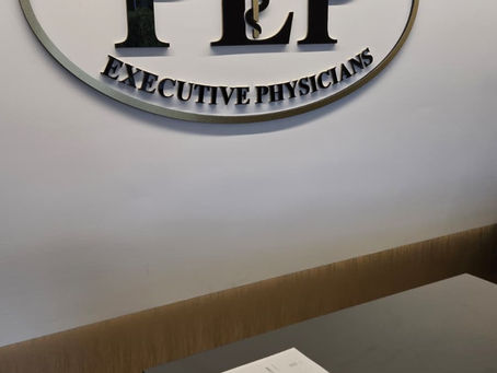 showcasing the luxury medical reception area at Executive Physicians of South Miami, featuring custom gold-trimmed signage installed over smooth DYW22103 wallcoverings near me with wood-grain accents