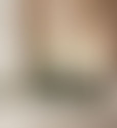 Luxurious living room with green sofa, floral mural, and high ceilings. Warm lighting, large windows, and a table with oranges in alcove.