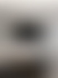 Modern living room with a sleek TV, gray walls, geometric shelves, a marble table, a vase with flowers, and abstract art, creating a calm vibe.