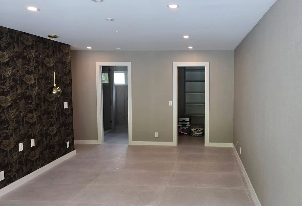 Room with gray walls, two open doorways, and a patterned dark accent wall. One doorway leads to a lit space; the other shows shelves.