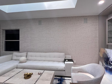 Large living room accent wall in a Delray Beach Polo Club home installed with TWC0705 designer wallcovering featuring an abstract taupe and off-white labyrinth line pattern behind a cream sectional sofa.