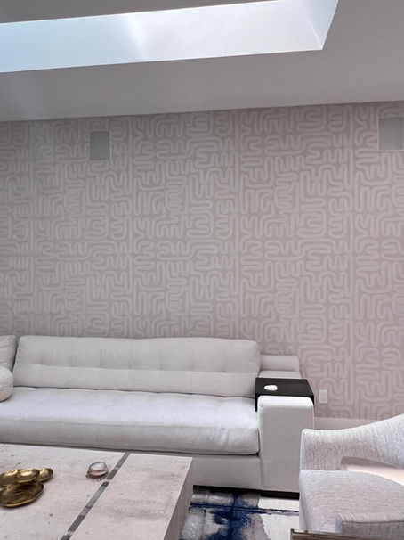 Large living room accent wall in a Delray Beach Polo Club home installed with TWC0705 designer wallcovering featuring an abstract taupe and off-white labyrinth line pattern behind a cream sectional sofa.