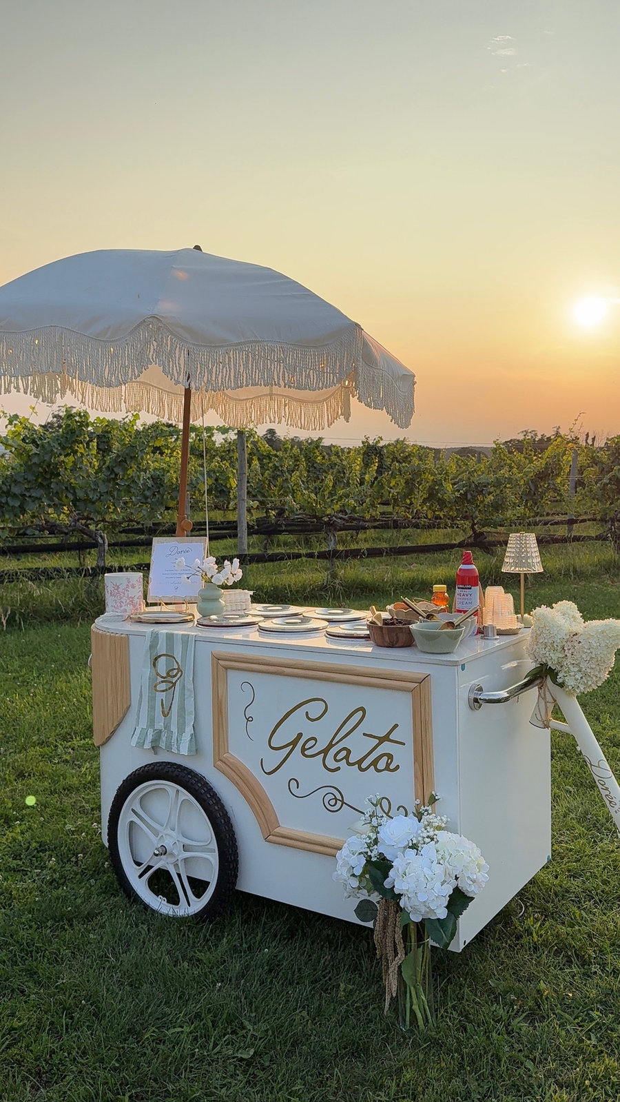 The Dorée Gelato cart under a fringed umbrella at sunset in a vineyard