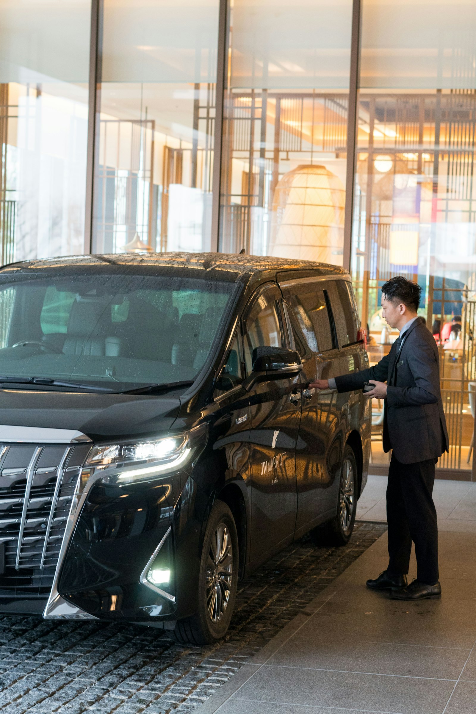 Chauffeur in a suit opening the door of a black luxury vehicle