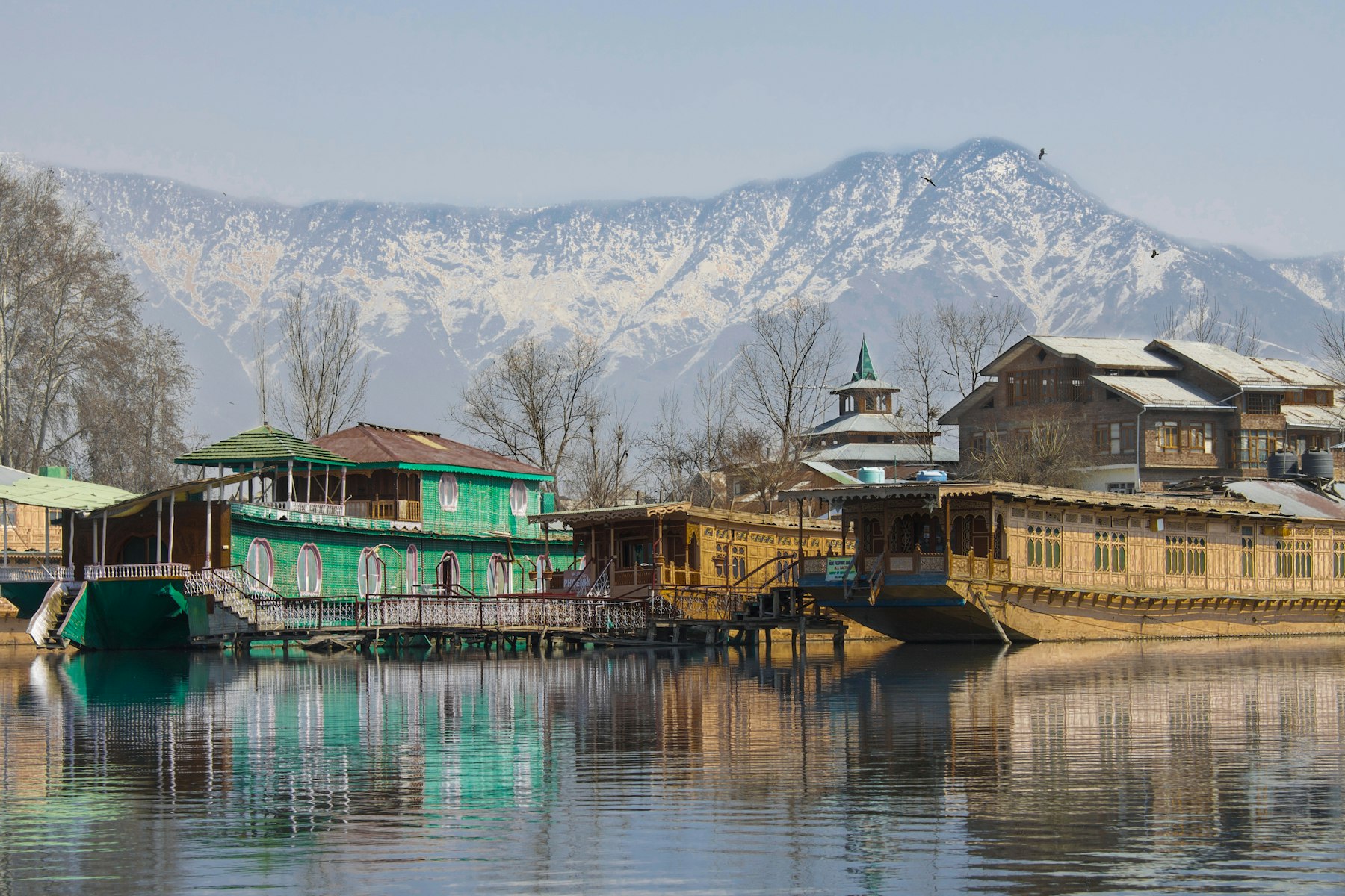 Houseboat on a lake beneath snowy mountains in Kashmir