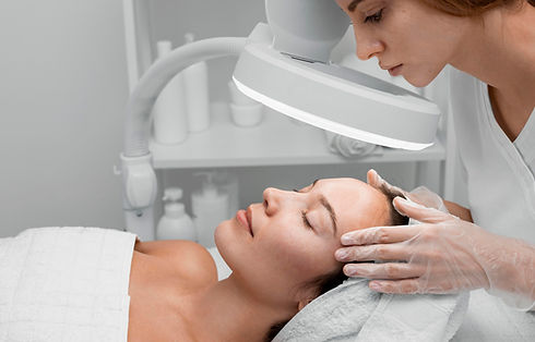 Beautician examining client's face using a lamp