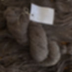 natural dark grey merino worsted yarn skein with yarn in the background