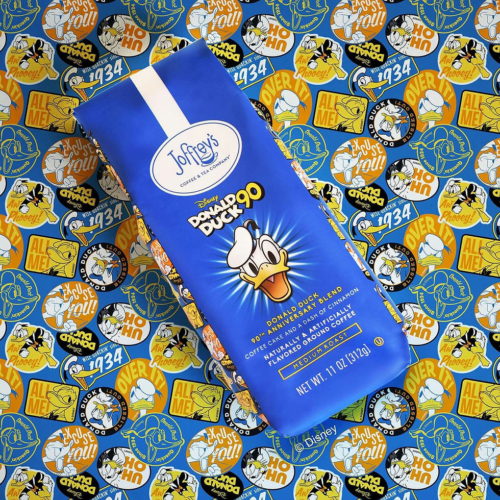Blue coffee bag with Donald Duck image, labeled "Donald Duck 90th Anniversary Blend". Background shows colorful Donald Duck patterns. This is the Joffrey's Donald Duck coffee blend.