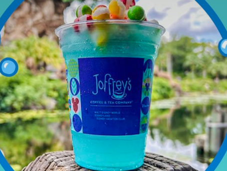 Blue drink with colorful toppings in a cup labeled "Joffrey's," set against a blurred green landscape. Bubbles frame the image.