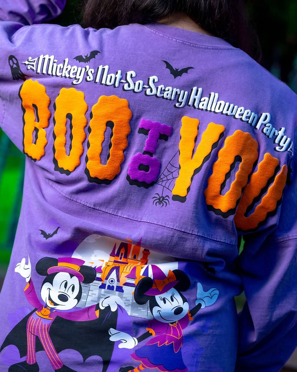 Person wearing a purple Halloween shirt featuring Mickey and Minnie in costumes, and text reading "Mickey's Not-So-Scary Halloween Party, BOO TO YOU."