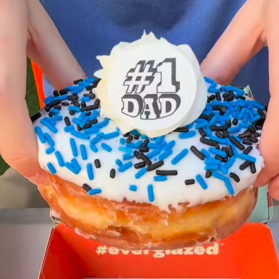 Hands holding a donut with white icing, blue and black sprinkles, and a "#1 Dad" topper. Orange box beneath with "#everglazed" text.