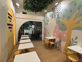 Hundred acre creamery with tables and chairs, tree-designed wall