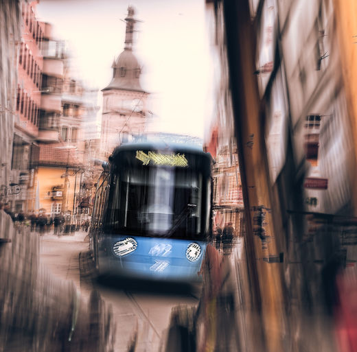 A blue Oslo tram emerges in soft blur, framed by scaffolding and old city buildings. The motion and distortion stretch the scene into a fleeting moment, where the past and present collapse into a dreamlike rush of steel, stone, and movement.