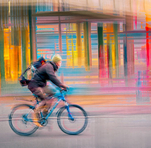 A cyclist cuts through Oslo’s glowing streets as luminous bands of colour melt into one another — amber, turquoise, and neon red dissolving into a painterly urban haze. Captured at nightfall as the city transforms into liquid light, where architecture and motion fuse into a vibrant, electric atmosphere. Energy surges through the frame, yet beneath the rush there’s a sense of quiet determination — a solitary figure navigating the sweetness and chaos of the city on his own rhythm. Limited Edition fine art by Douglas Carr.