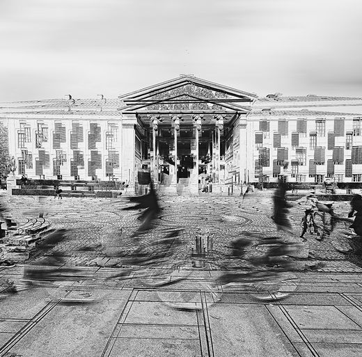 In front of the iconic University of Oslo, fleeting figures blur across the cobblestone square—cyclists, walkers, moments in motion. This dynamic black-and-white abstract captures the energy and transience of urban life at University Square, where history and modern rhythms collide. The ghostlike presence of passersby reflects a world in constant flux, evoking themes of imperamanence, progress, and quiet contemplation amid movement. A Limited Edition Digital Graphic Artwork by Douglas Carr