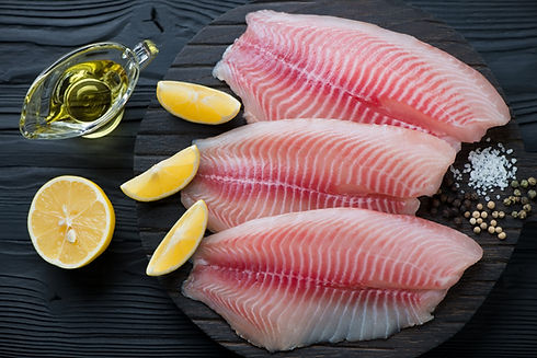 Raw fresh tilapia fillets with seasonings ready to be cooked, top view.jpg
