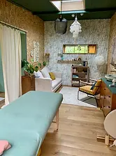Salle de bien-être avec table de massage, rideau et tapis, prête pour une séance relaxante.