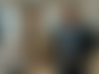 A smiling student with a backpack listens to a suit-clad man in an office. A laptop displays text. Bright, modern interior.