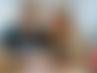 Smiling man and woman in business attire review papers in an office with a city skyline background. A Canadian flag is on the desk.