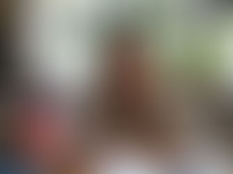 Young woman smiling while writing at a desk with a Canadian flag, in a bright room with plants, conveying a cheerful mood.