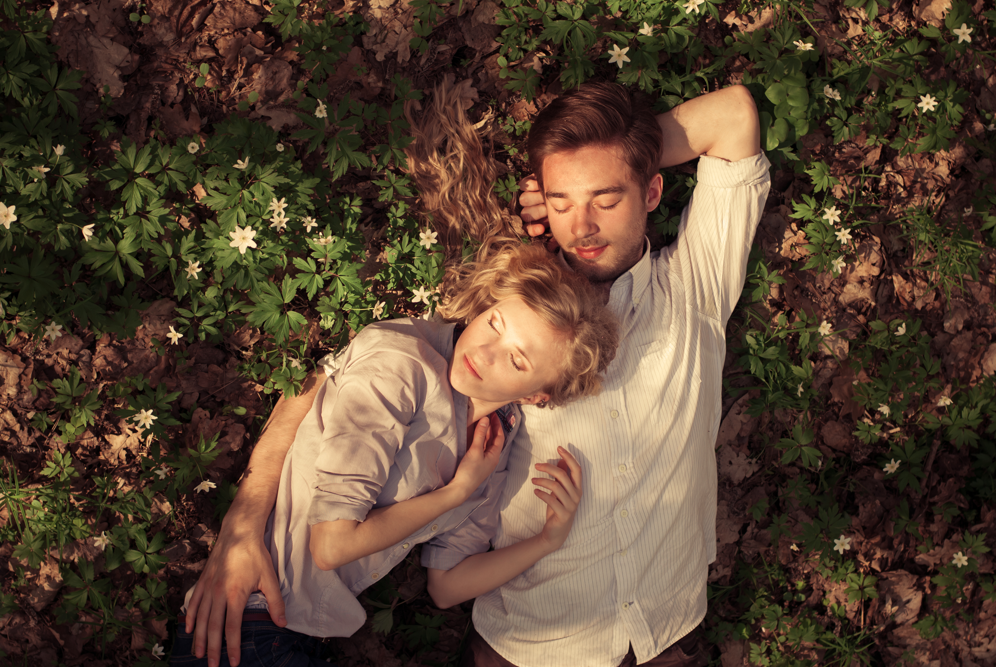 Couple embracing, asleep in a flowering meadow
