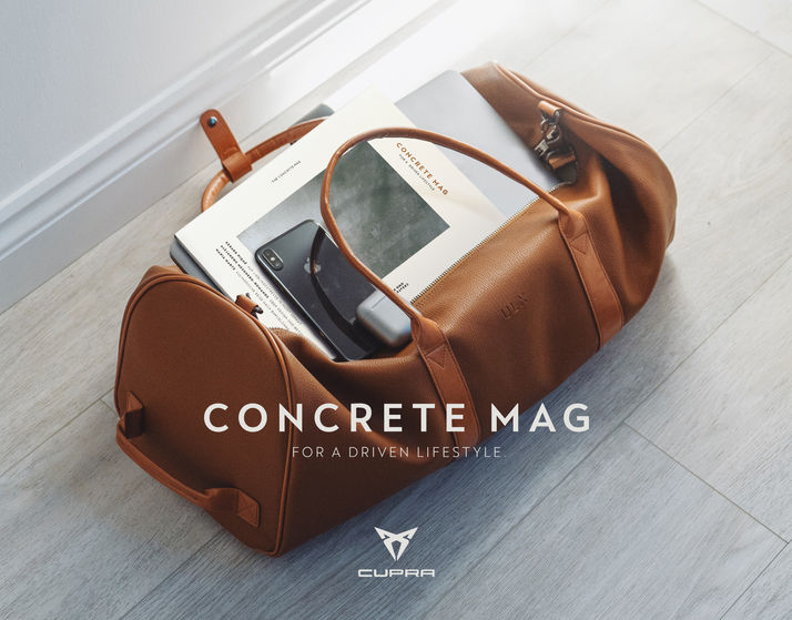 duffle leather bag holding a laptop, a cupra lyfestyle magazine, and an iphone.