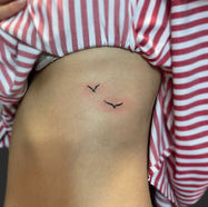 Small bird tattoos on a person's side