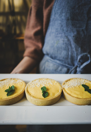 A Girl holding a plate of lemon custard tard in a french cafe bakery.
