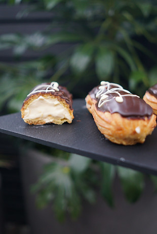 In house-made cream filled in an eclair topped with chocolate