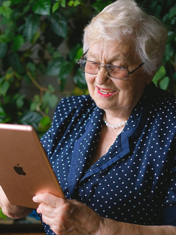 Older woman using a tablet outdoors.