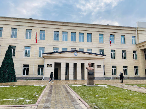 Building facade with flags, statues, and text; kyrgyzstan medical universities near campus.