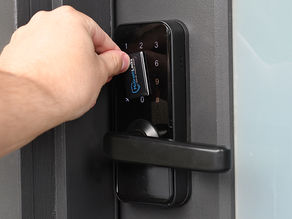 Hand using rfid card on black digital door lock with keypad