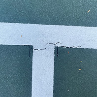 cracks form on line striping on green tennis court