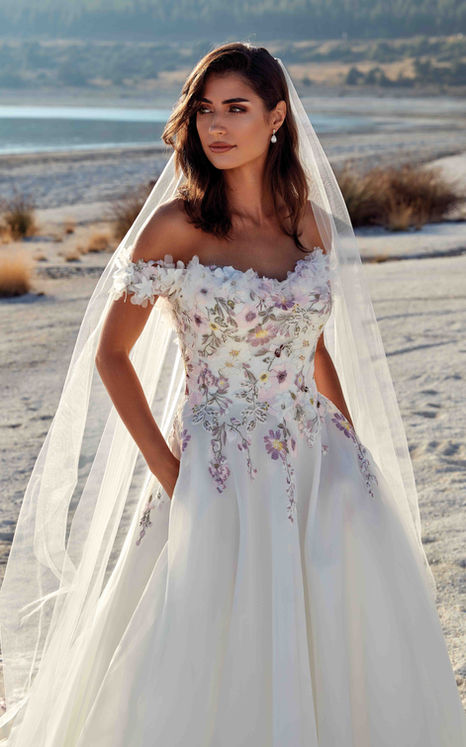 Eddy K Ballgown with multi colored lace on brown haired woman with veil standing on sandy beach