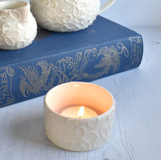 Handmade porcelain tea light holder decorated with slip-trailed daisies and glazed in clear.
