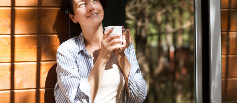 Woman drinking tea outside enjoying sunshine to reduce lower cortisol in menopause and stress