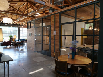 Iona Work Spaces Conference Room. Picture taken outside of conference room. Includes glass walls, tables, and chairs.