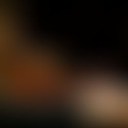 A person plays a violin with a focused mood, using a bow. The image is close-up, highlighting the violin's warm wood tones against a dark background.