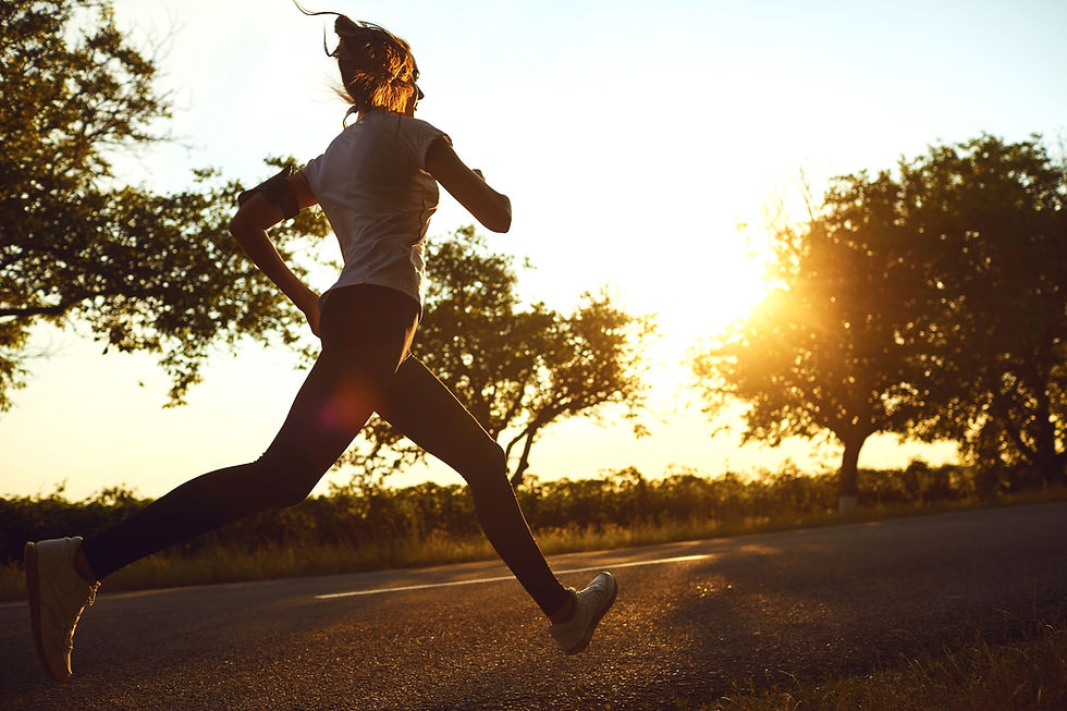 Silhouette of a woman running on a country road at sunset, with trees and golden sunlight glowing behind her.